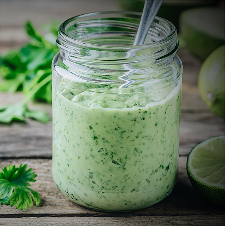 green salad dressing with avocado, lime and cilantro in a glass